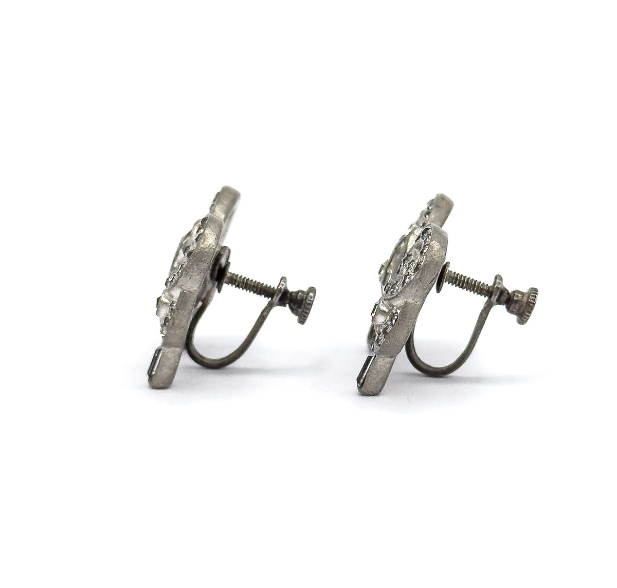 Both earrings seen edge-on in profile, showing how slim and flat the bows sit while the threaded screw posts, knurled knobs and curved wire arms extend to one side.