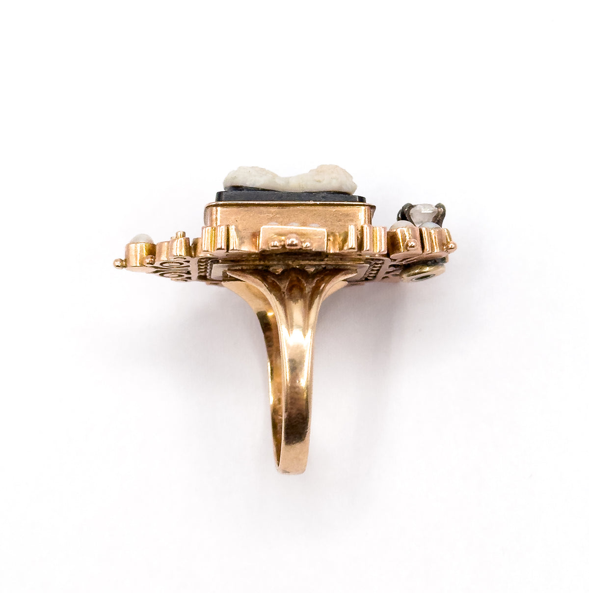 Victorian hardstone cameo, seed pearl and diamond ring in 9K rose gold, shown upright from the side so the tapering shank, raised bezel and stepped openwork gallery stand clear against white.