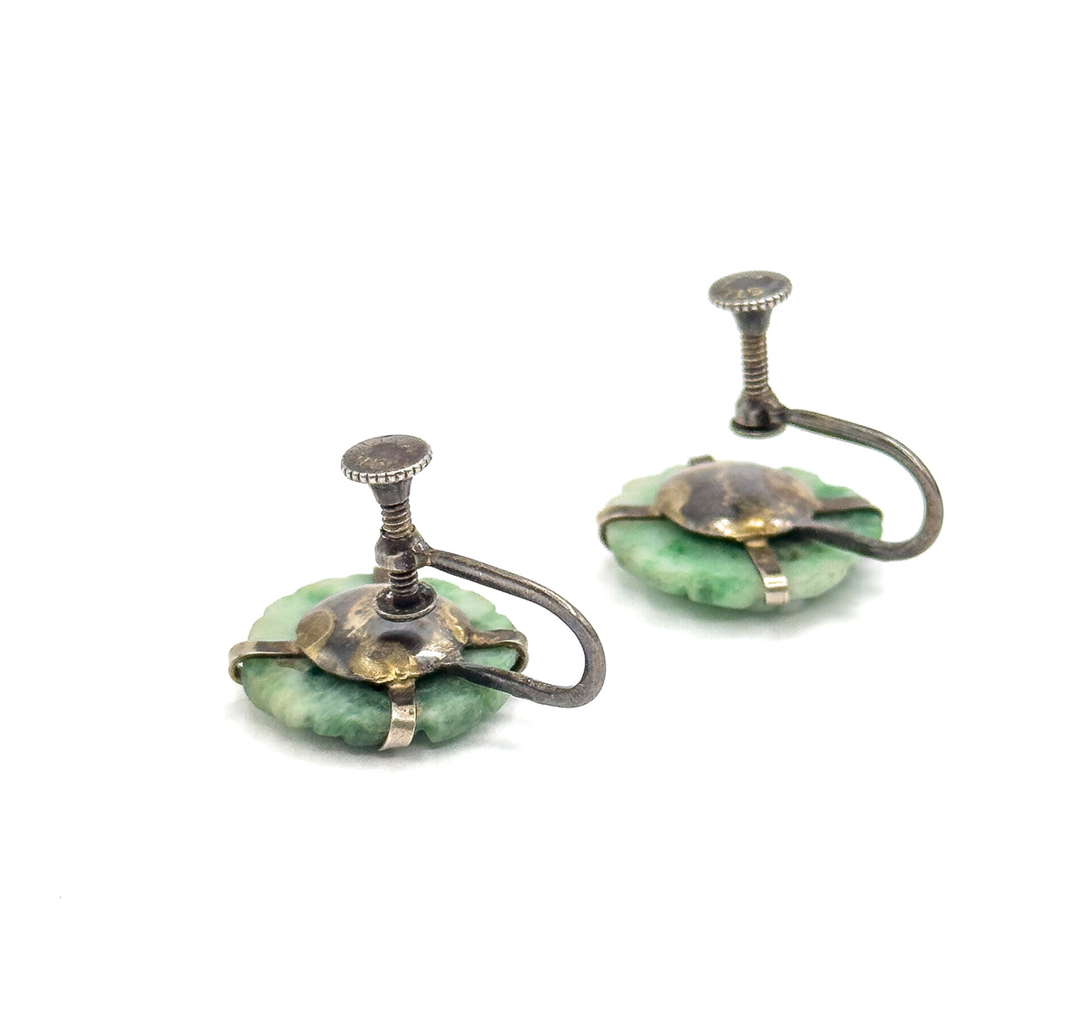 Angled three-quarter view from behind, showing how the jade discs sit low beneath the domed silver backplates while the screw arms and milled discs rise to the side.