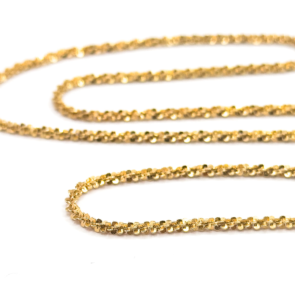 The chain doubled back in soft S-curves, the nearest row sharp against a blurred background so the beaded texture of each popcorn link stands out in relief.