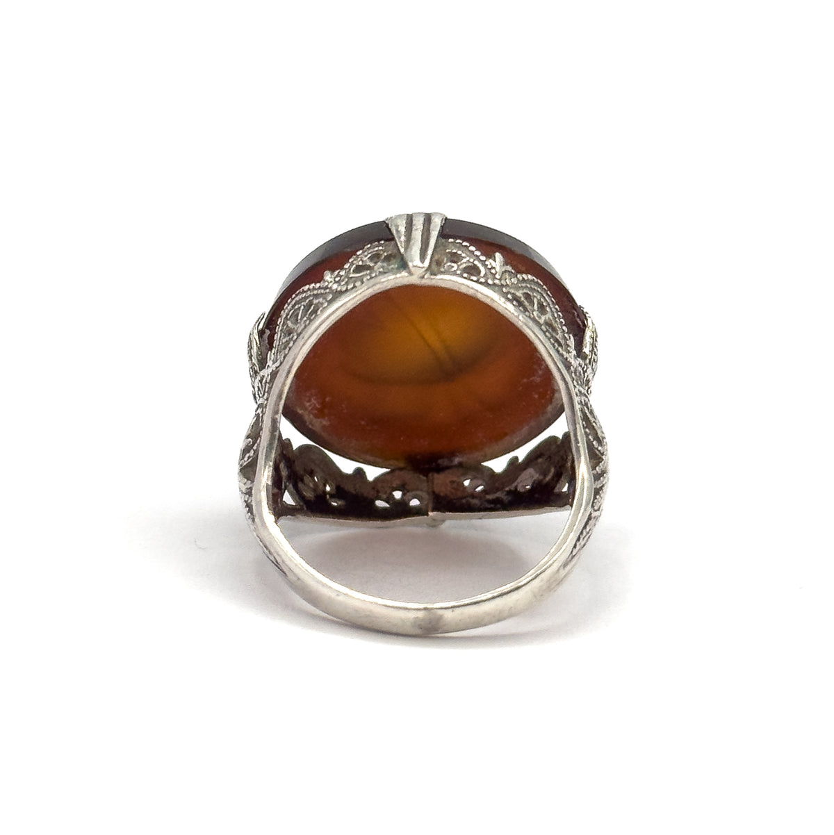 Back view through the shank opening, light passing through the underside of the rootbeer quartz to show its translucent depth within the sterling silver prongs and filigree gallery.