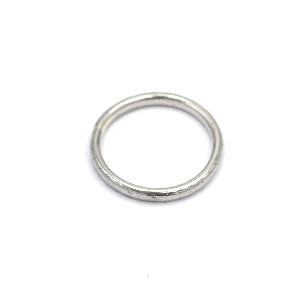 Viewed from above at a slight tilt, the band lies flat so the circular opening reads as a full round hole, the slim domed shank forming an even ring with soft light along its upper curve.