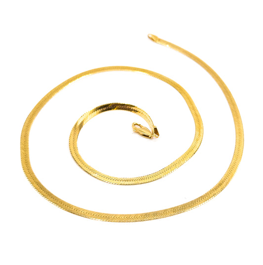 The full chain spiralled wide across white with one flat tapered end lifting free at the upper right, while the lobster clasp sits alone at the centre of the coil.