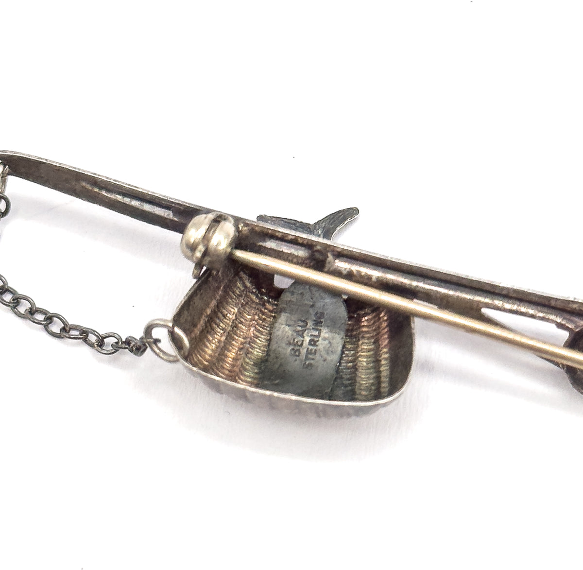 Reverse view showing the BEAU STERLING stamp on the flat back of the basket, with the pin stem crossing the pole and the safety chain linked at the edge.