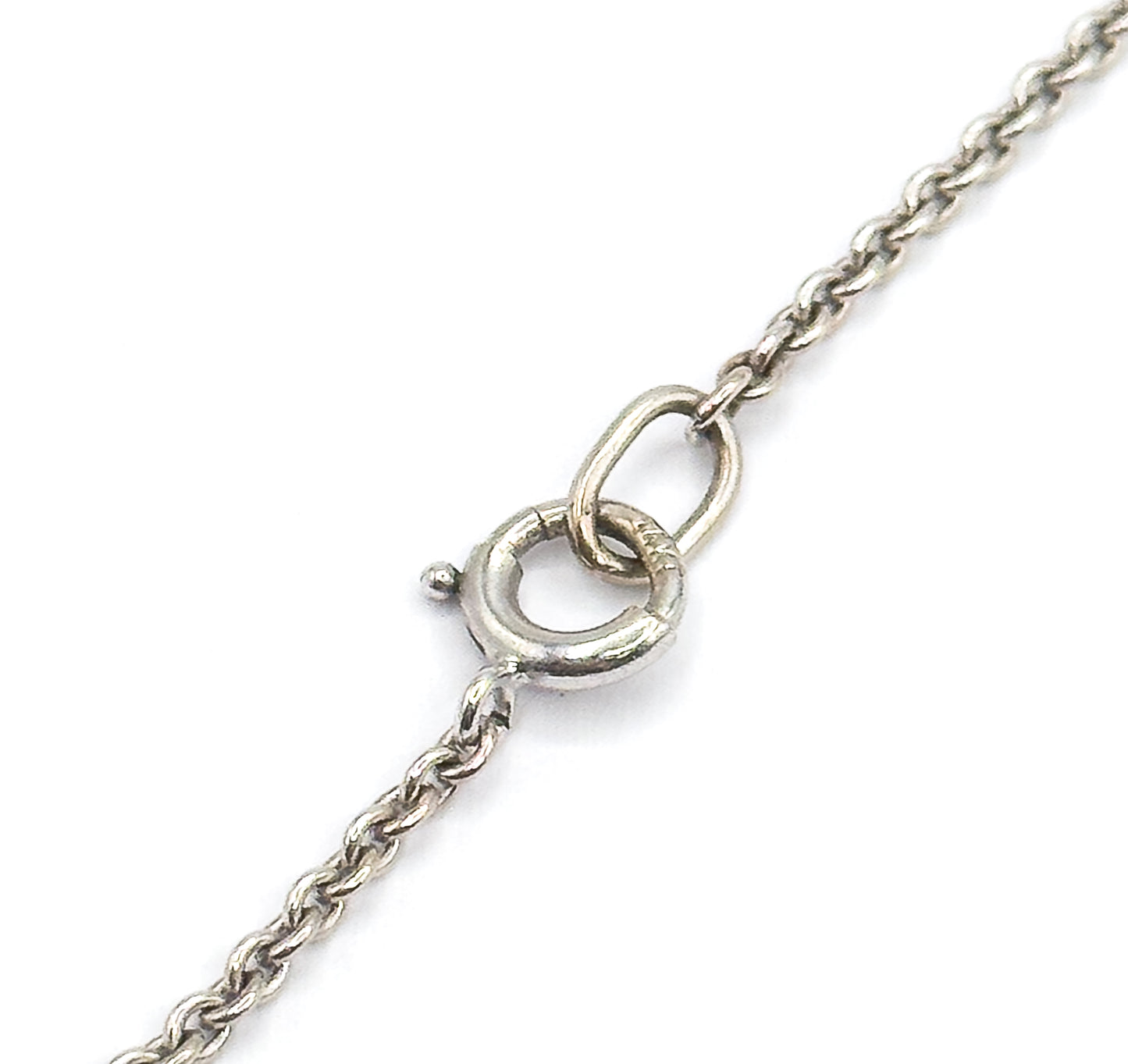 Close view of the white gold chain's spring ring clasp hooked through an oval link, showing the fine round cable links running away in both directions.