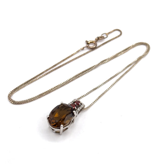 Angled three-quarter view with the chain sweeping in a long diagonal loop to the clasp at the top, the pendant tipped forward at the lower edge so the prongs along the quartz rim show.