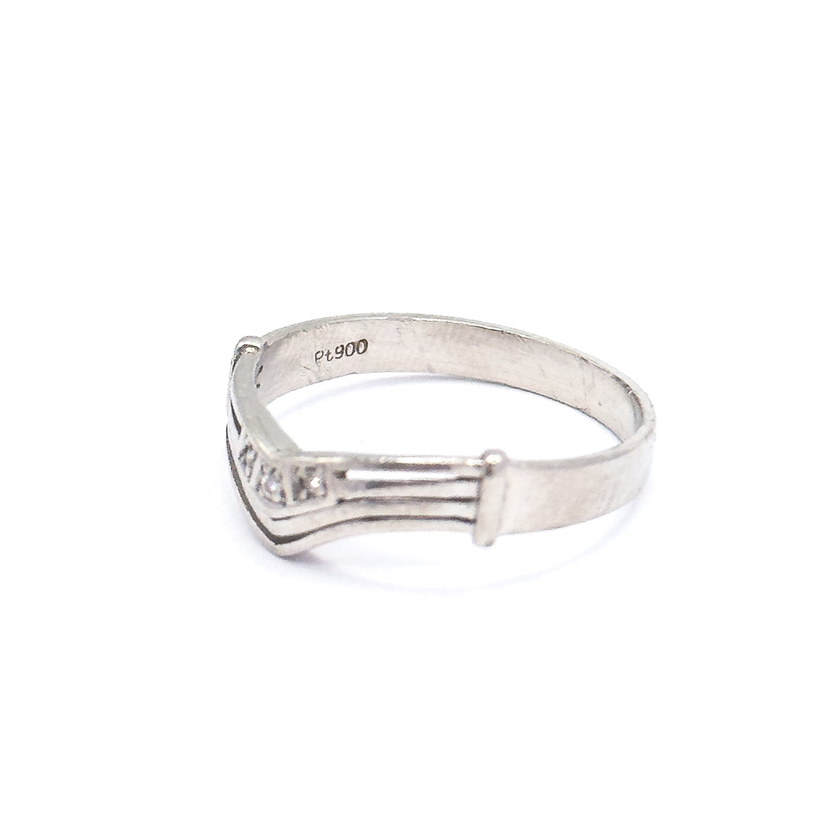 Angled interior view into the band, where a small maker's stamp sits on the smooth inside of the shank, with the grooved chevron and its three tiny diamonds seen from below at the left.