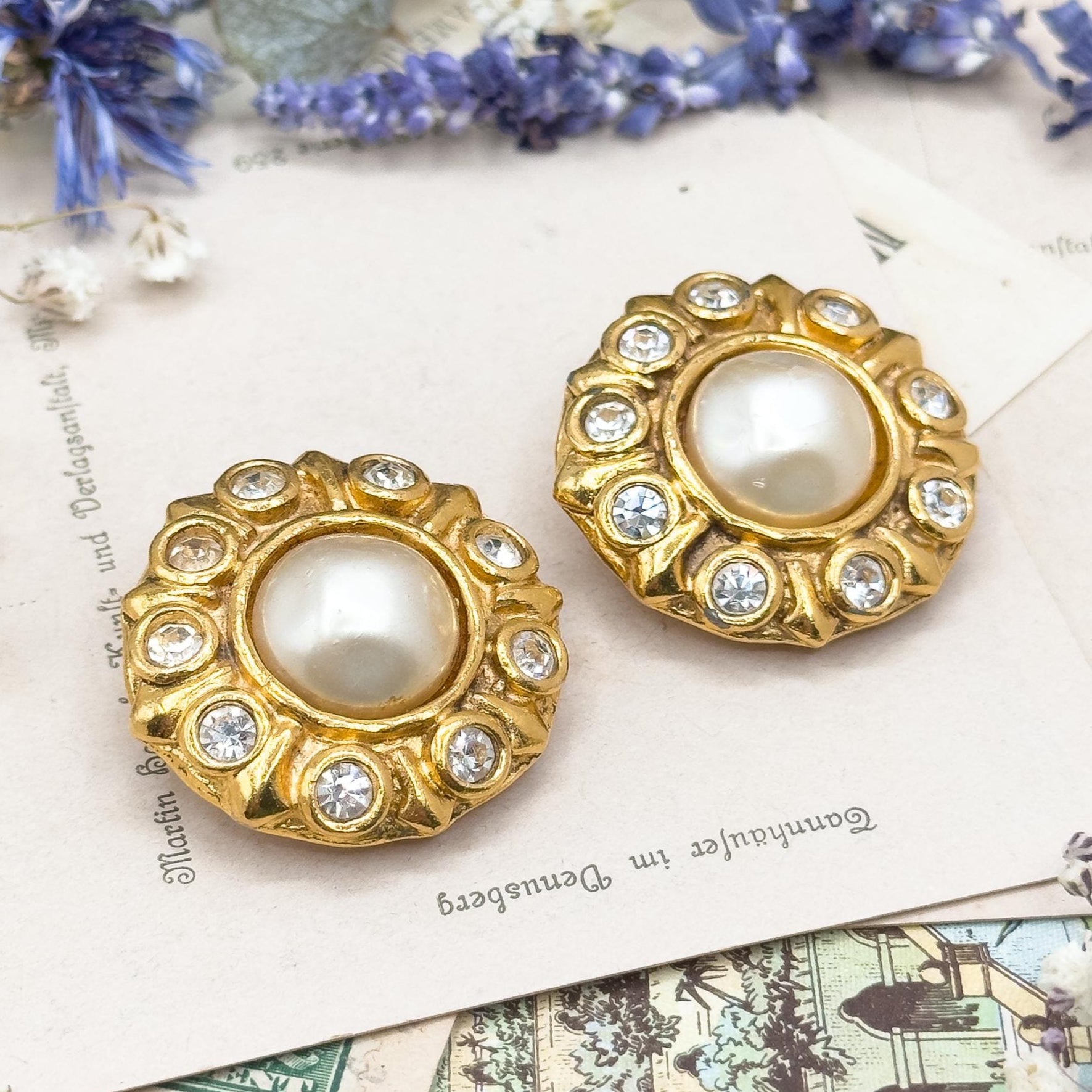 Gold earrings with pearl centers on a decorative background