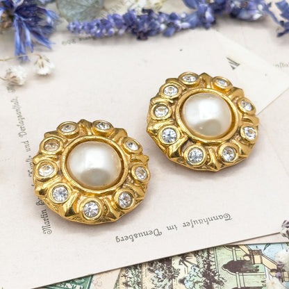 Gold earrings with pearl centers on a decorative background