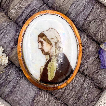 Oval brooch with a portrait on fabric with flowers