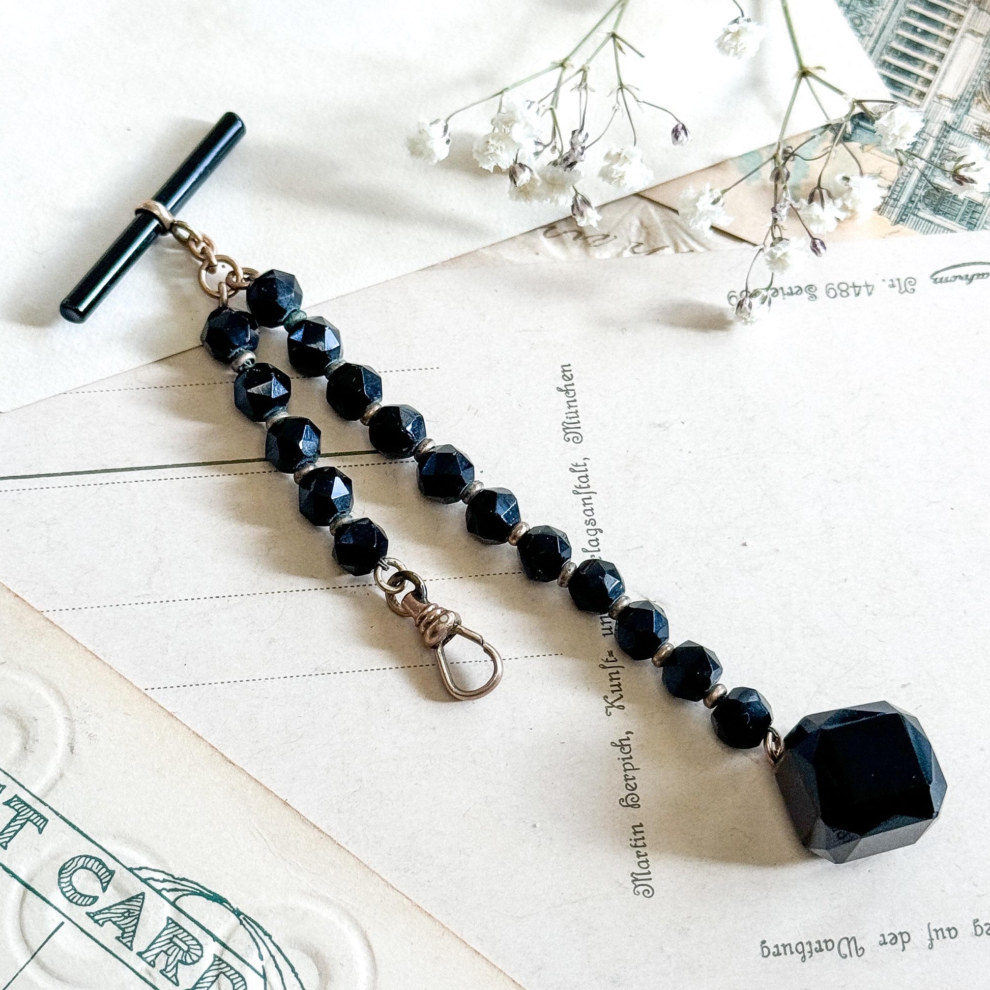 Black beaded necklace with a large pendant on a textured surface
