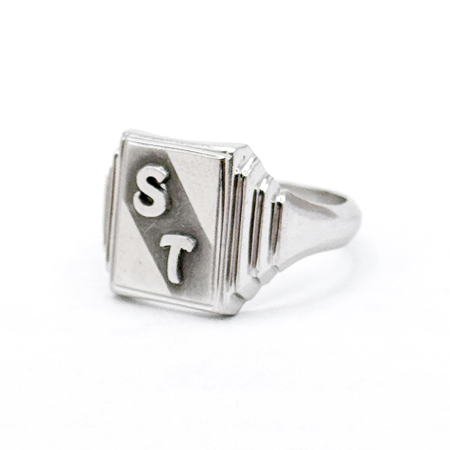 Silver ring with 'ST' engraving on a white background
