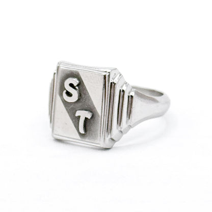 Silver ring with 'ST' engraving on a white background