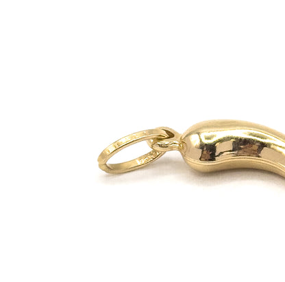Close crop on the top end of the charm, filling the frame with the round yellow gold bale and its faint stamping where it joins the broad puffed shoulder of the horn.
