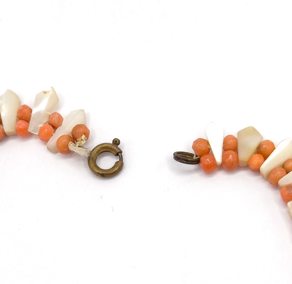 The two ends of the necklace laid open on white, showing the base metal spring ring clasp on one side and the small jump ring on the other, cord ends visible.