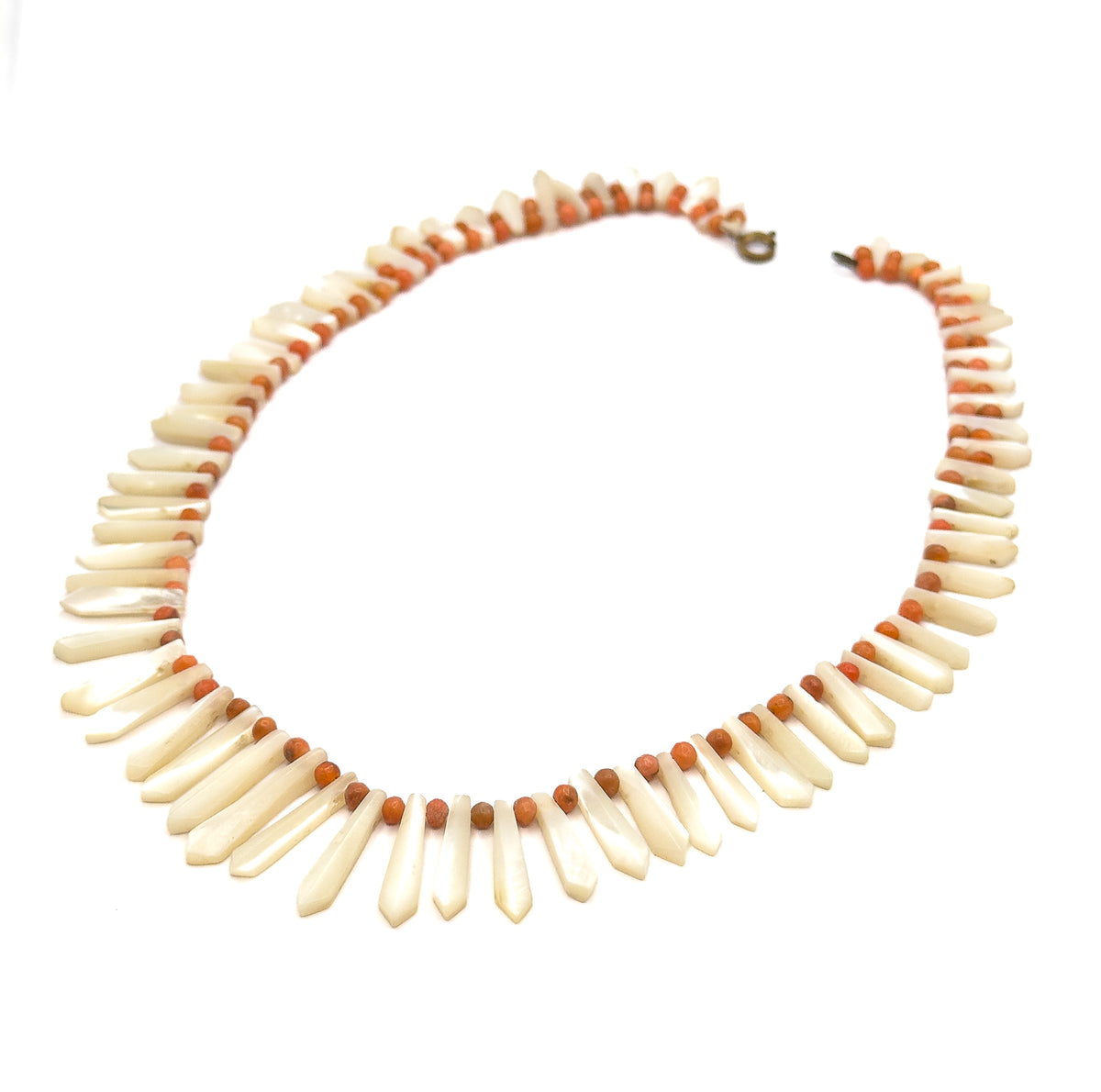 The whole necklace laid out as an open oval on white, the full circuit visible at once with the clasp at the top and the pickets lengthening steadily toward the bottom centre.