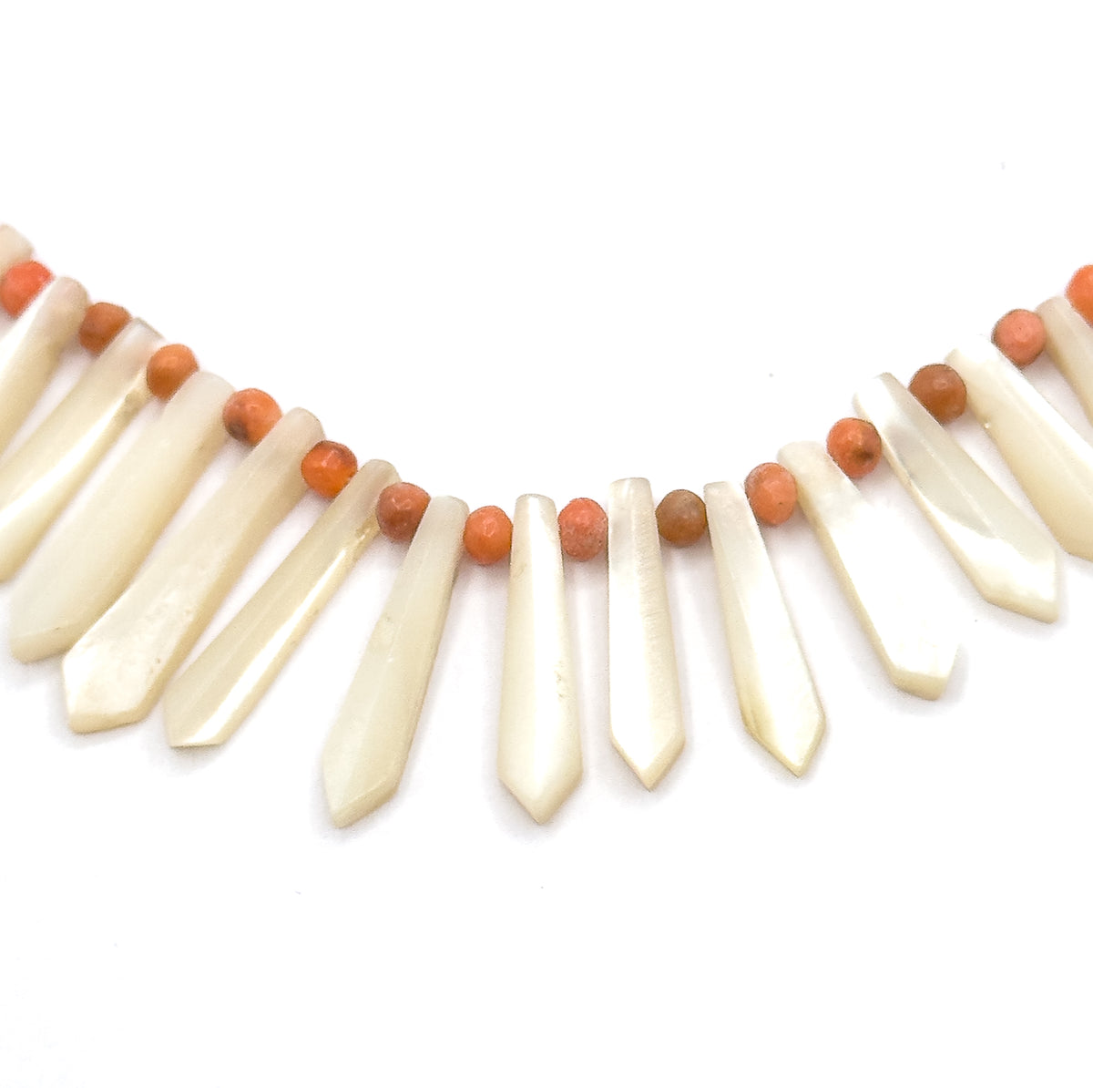 A tight close-up of the centre front, showing the flat facetted faces of the mother of pearl pickets and the round coral beads strung above each gap along the cord.