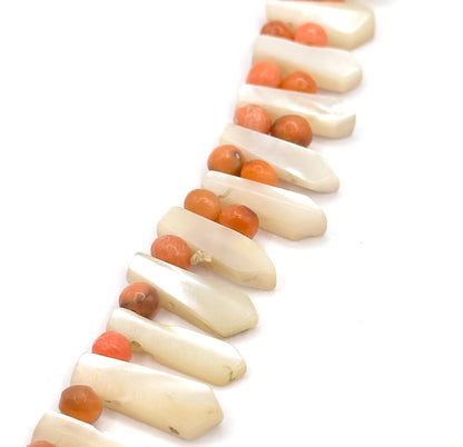 A diagonal run of the strand across the frame, following the pickets as they widen toward the lower edge with a small coral bead tucked at the base of each one.