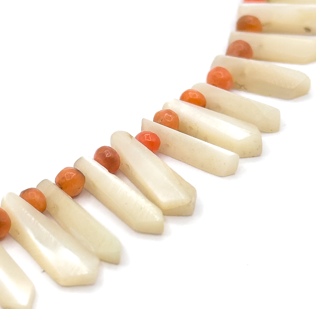 A low, raking view from the pointed ends, where the nearest pickets loom large and sharply lit while the row recedes into softer focus, each coral bead sitting at the top of its drop.