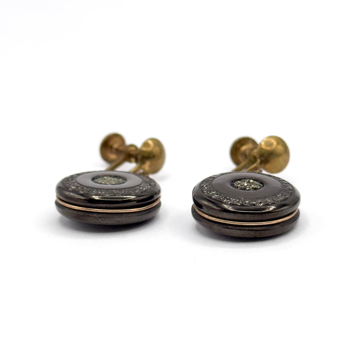 A near side-on view at disc level, revealing the stacked profile of each anthracite disc with the rose gold filled wire running around the lower edge and the screw fittings rising behind.