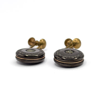 A near side-on view at disc level, revealing the stacked profile of each anthracite disc with the rose gold filled wire running around the lower edge and the screw fittings rising behind.
