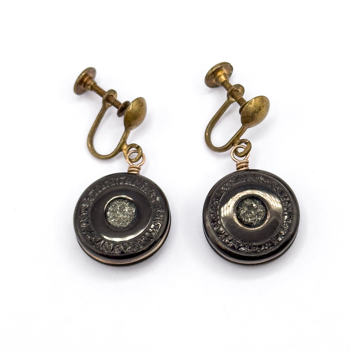 The pair stands upright side by side, screw fittings at top and discs below, the right-hand disc tilted so light catches the rose gold filled rim around its pyrite centre.