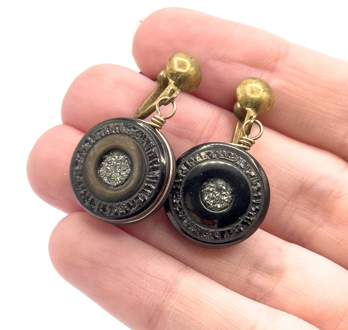 Victorian pyrite disc drop earrings shown resting on fingers for scale, each round black anthracite disc with a sparkling pyrite centre hanging from wire and a ball-topped screw back.