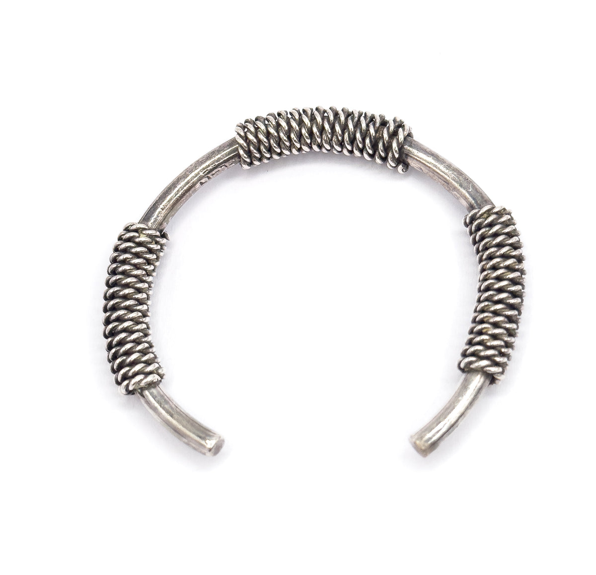 Overhead view of the cuff alone on white, its opening facing downward, with one broad coil at the top of the arc and two longer coiled sections flanking the tapered terminals.