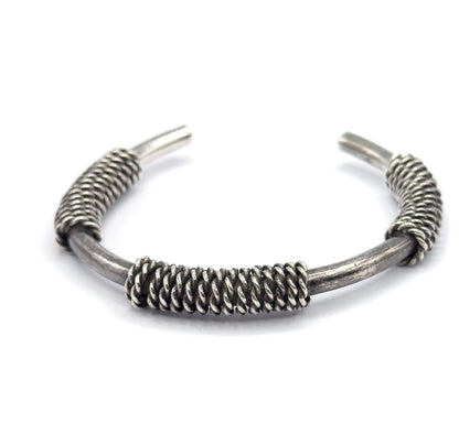 Front-on view at eye level with the broad central coil filling the foreground and the sterling silver band arching up and away to the two tapered terminals splayed at the top.