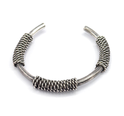 Overhead view with the opening uppermost, the central coil now at the bottom of the arc and the two tapered terminals pointing up and apart, patina dark between the twisted strands.