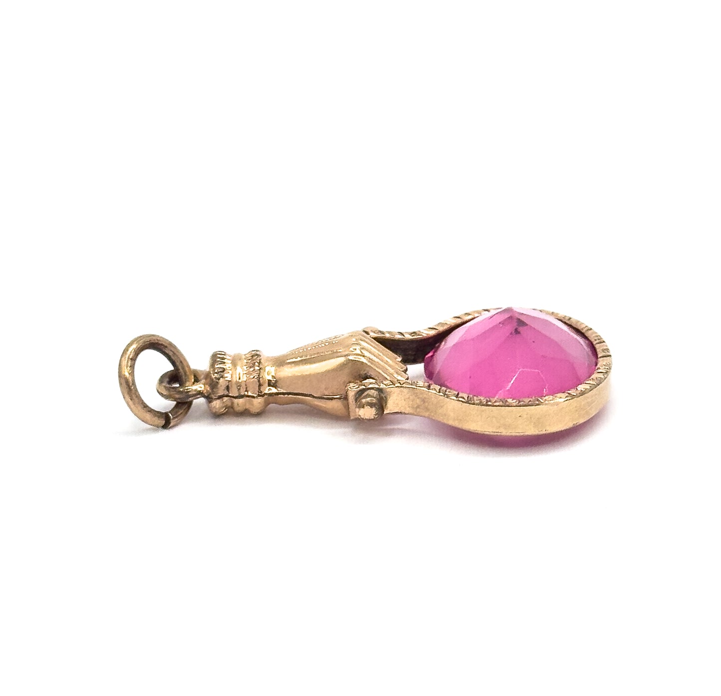 Side profile on white, the fob lying horizontally so the round ring, ribbed cuff and gripping fingers lead to the deep pink glass seated in its engraved bezel.