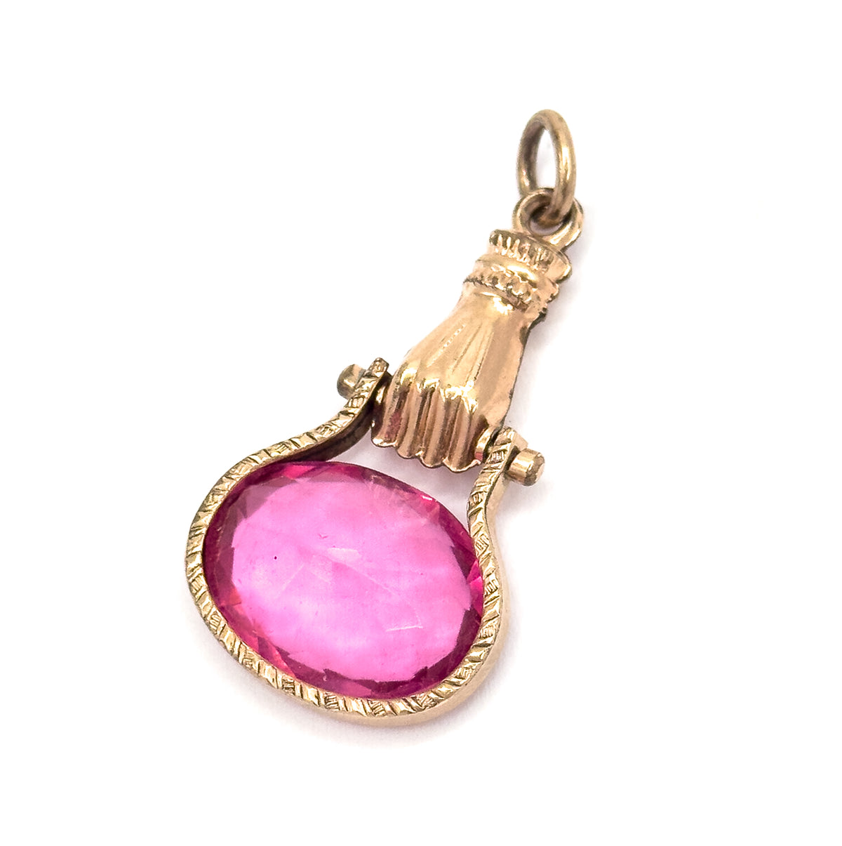 Diagonal view with the fob leaning back, the knuckles and cupped palm catching the light while the oval pink glass tilts toward the viewer in its engraved bezel below the pivot lugs.