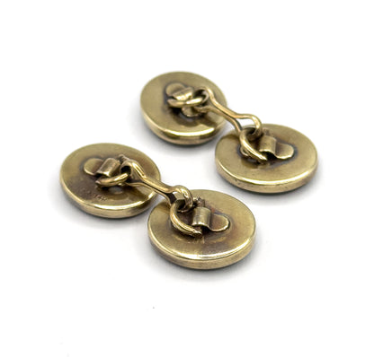 Both cufflinks together from the reverse, all four plain oval yellow gold backs and their curved link bars angled towards the viewer.