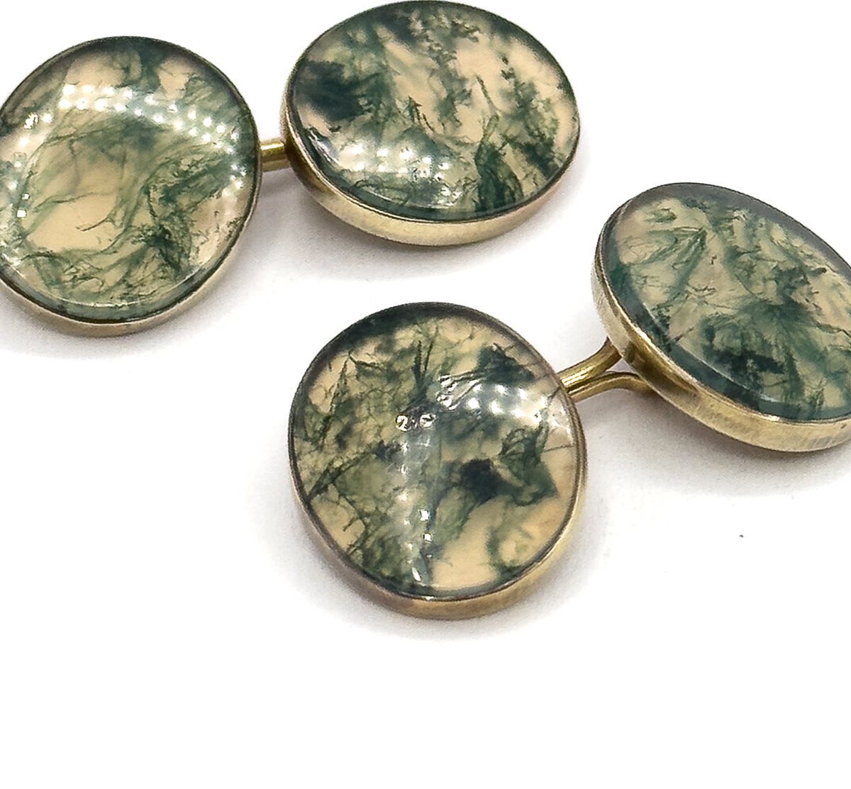 Close overhead view filling the frame with all four moss agate faces, their deep green veining and cream ground clear inside the yellow gold bezel rims, link bars joining each pair.