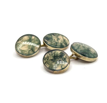 Low three-quarter view from the side, the four moss agate faces tilted towards the viewer so the yellow gold bezel walls and slim curved link bars show their shallow profile.