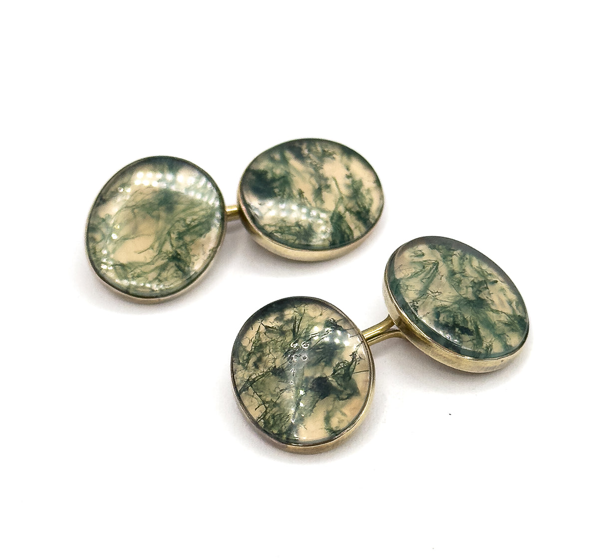 Both cufflinks laid apart on a diagonal, one pair upper left and one lower right, so each slim yellow gold link bar and the pairing of two moss agate faces per cufflink reads clearly.
