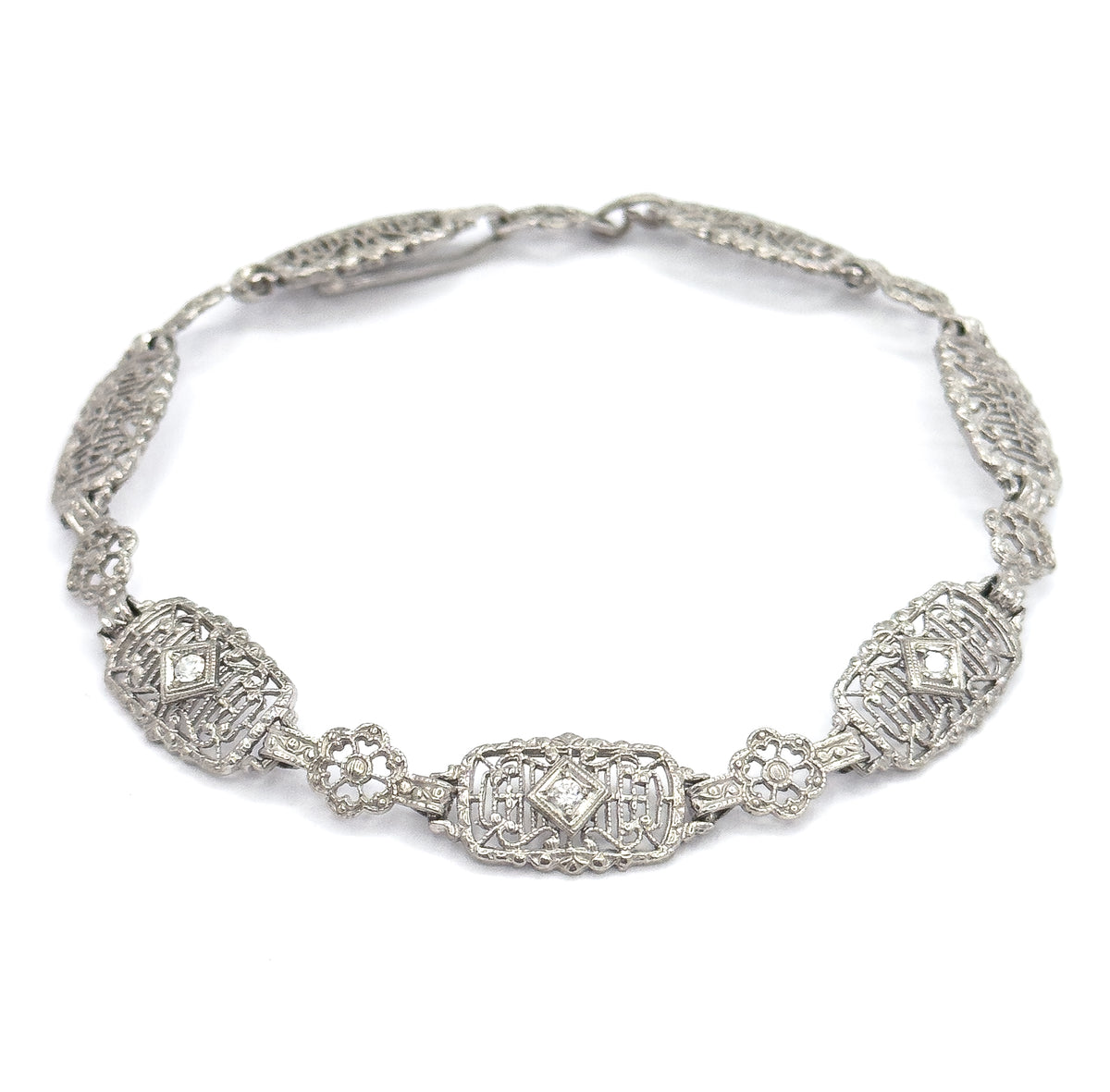 Viewed from slightly above, the closed loop brings the three diamond-set oval links forward along the lower curve, so all three prong-set stones catch the light together beneath the clasp.