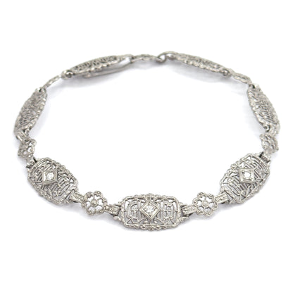 Viewed from slightly above, the closed loop brings the three diamond-set oval links forward along the lower curve, so all three prong-set stones catch the light together beneath the clasp.