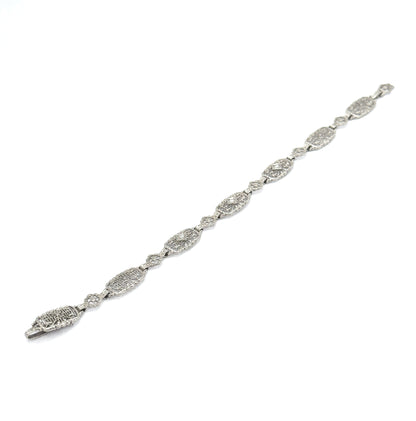 The whole bracelet laid out flat and stretched diagonally across a white background, showing its full length from clasp to end with the alternating oval and floral filigree links.