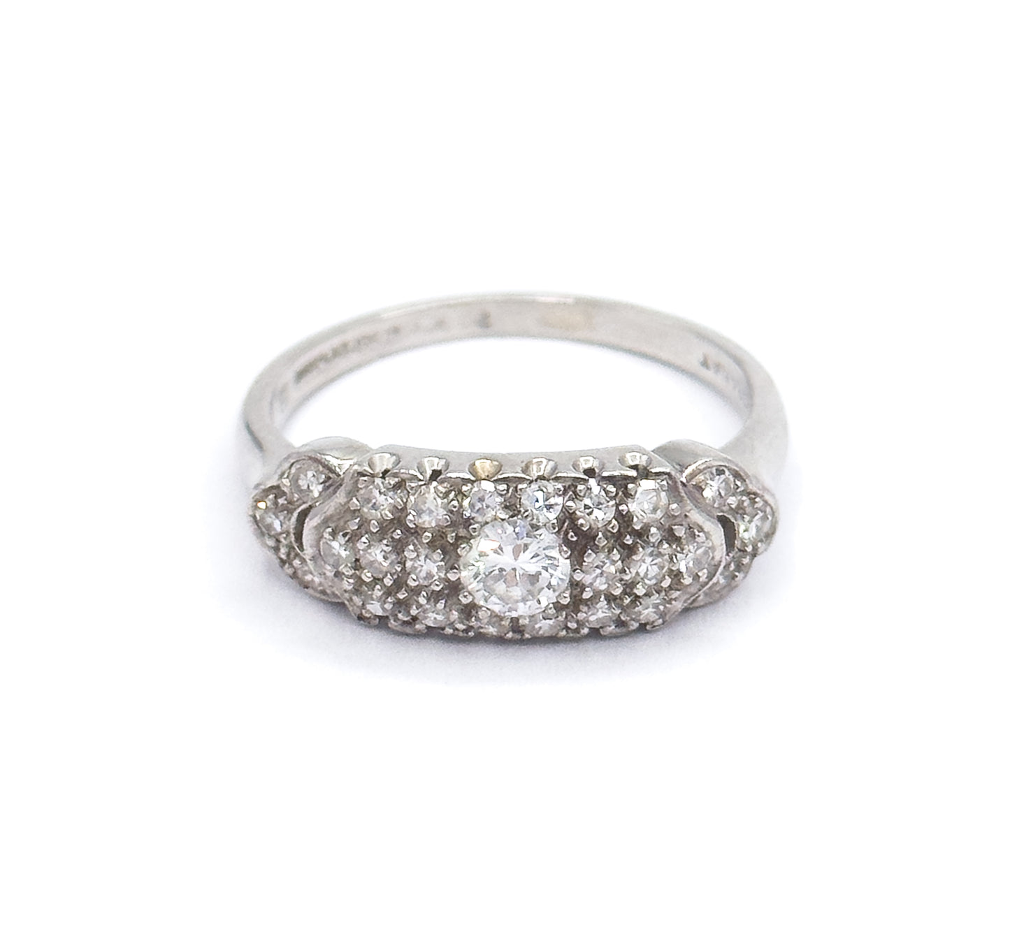 Straight-on front view against white with the domed pavé face level to the camera, the transitional cut centre diamond flanked by rows of smaller diamonds and the shank rising behind it.