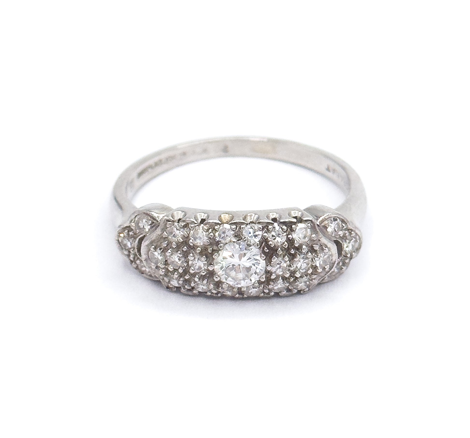 Straight-on front view against white with the domed pavé face level to the camera, the transitional cut centre diamond flanked by rows of smaller diamonds and the shank rising behind it.