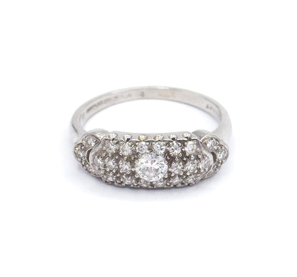 Straight-on front view against white with the domed pavé face level to the camera, the transitional cut centre diamond flanked by rows of smaller diamonds and the shank rising behind it.