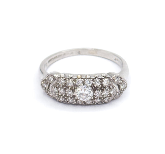 Straight-on front view against white with the domed pavé face level to the camera, the transitional cut centre diamond flanked by rows of smaller diamonds and the shank rising behind it.