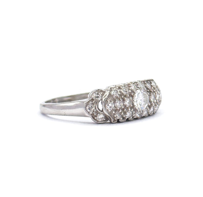 Side profile off the hand against white, the platinum shank rising to scalloped shoulders and the low-domed pavé head, its diamonds seen edge-on in rows.