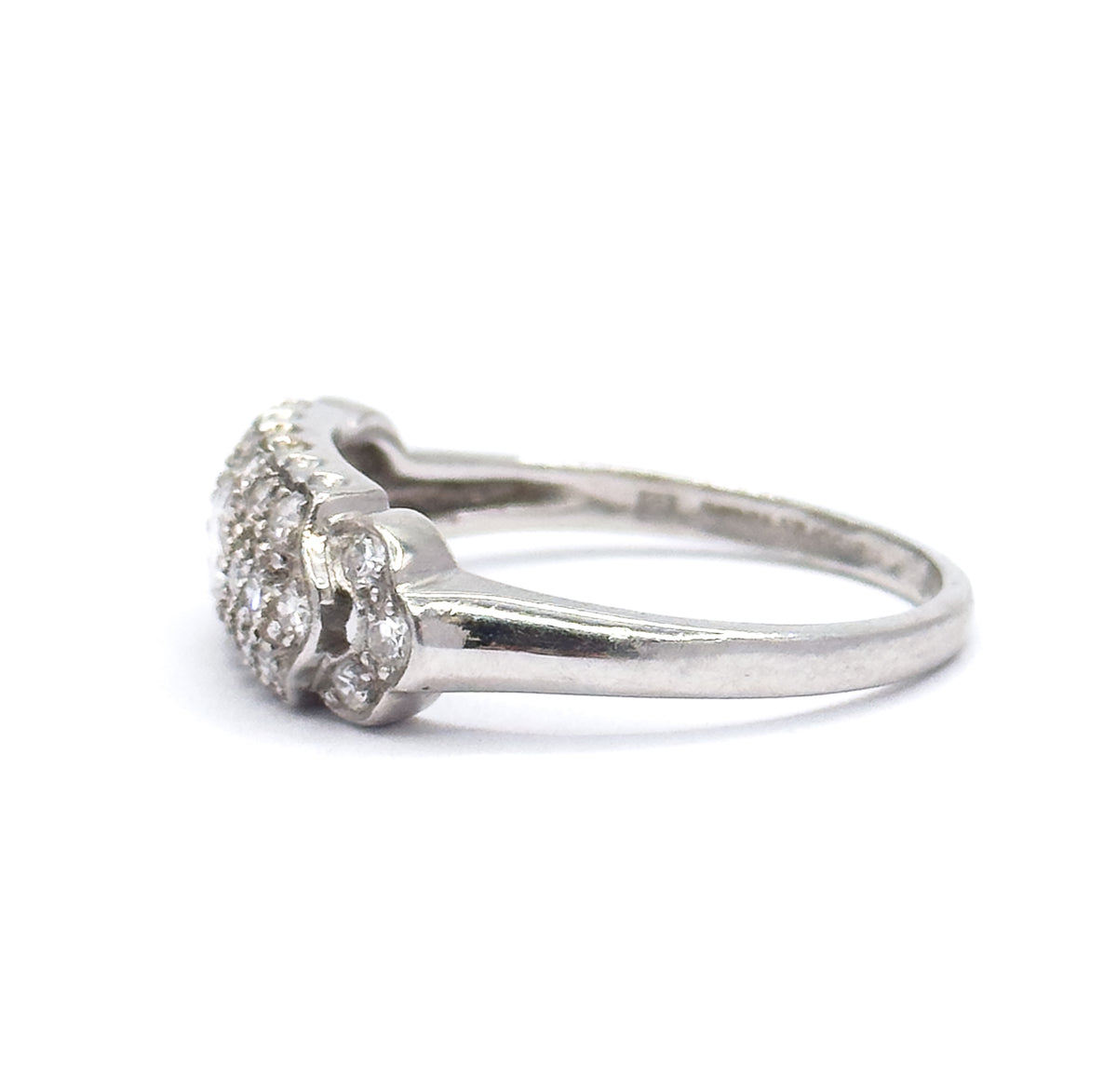 Profile from the opposite side against white, the pavé head at left with diamonds set into its scalloped shoulders, the platinum shank sweeping away to the right and narrowing at the back.