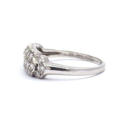 Profile from the opposite side against white, the pavé head at left with diamonds set into its scalloped shoulders, the platinum shank sweeping away to the right and narrowing at the back.