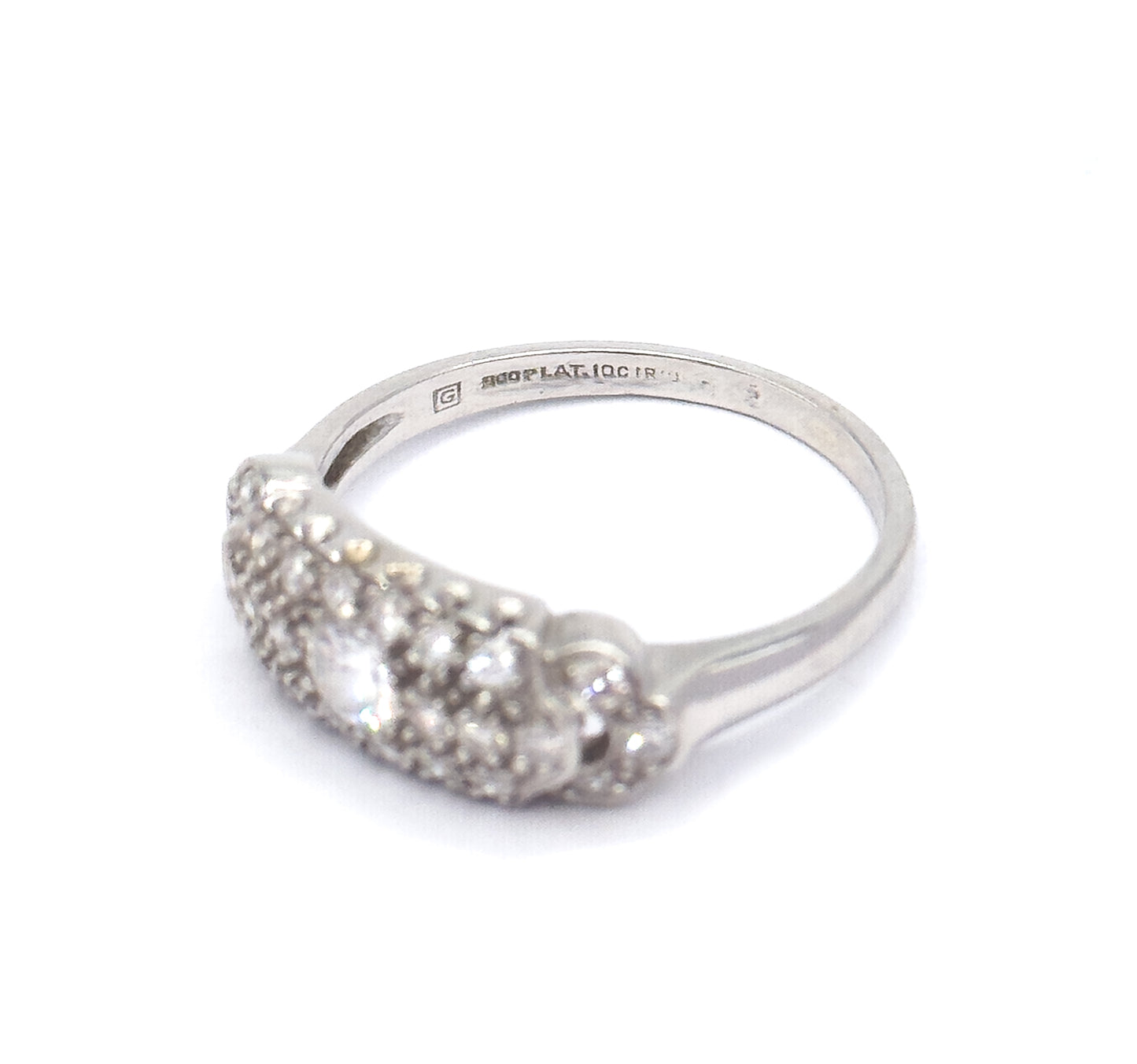 Angled three-quarter view against white with the ring tipped forward, bringing the stamped markings inside the platinum shank into view above the domed pavé head and its centre diamond.