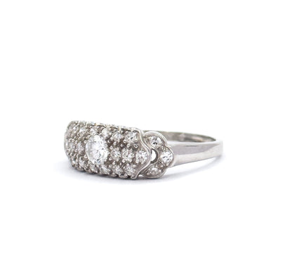 Low side-on view against white showing how the pavé head domes up above the shank, the transitional cut centre diamond sitting proud among smaller diamonds down the scalloped shoulder.