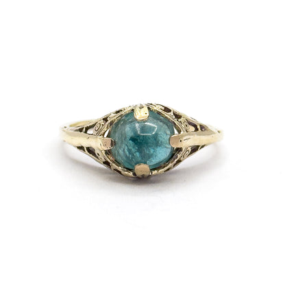 Straight-on view from directly above the ring lying flat, the round greenish blue cabochon centred between four prongs with the pierced fern gallery spreading symmetrically to each shoulder.