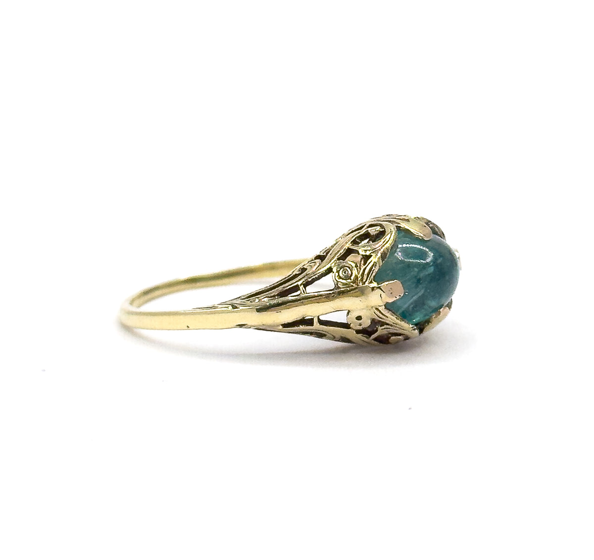 Direct eye-level profile of the ring against white, the cabochon seen edge-on in its prongs so the domed top and the airy pierced sidewall of the gallery stand out above the thin shank.